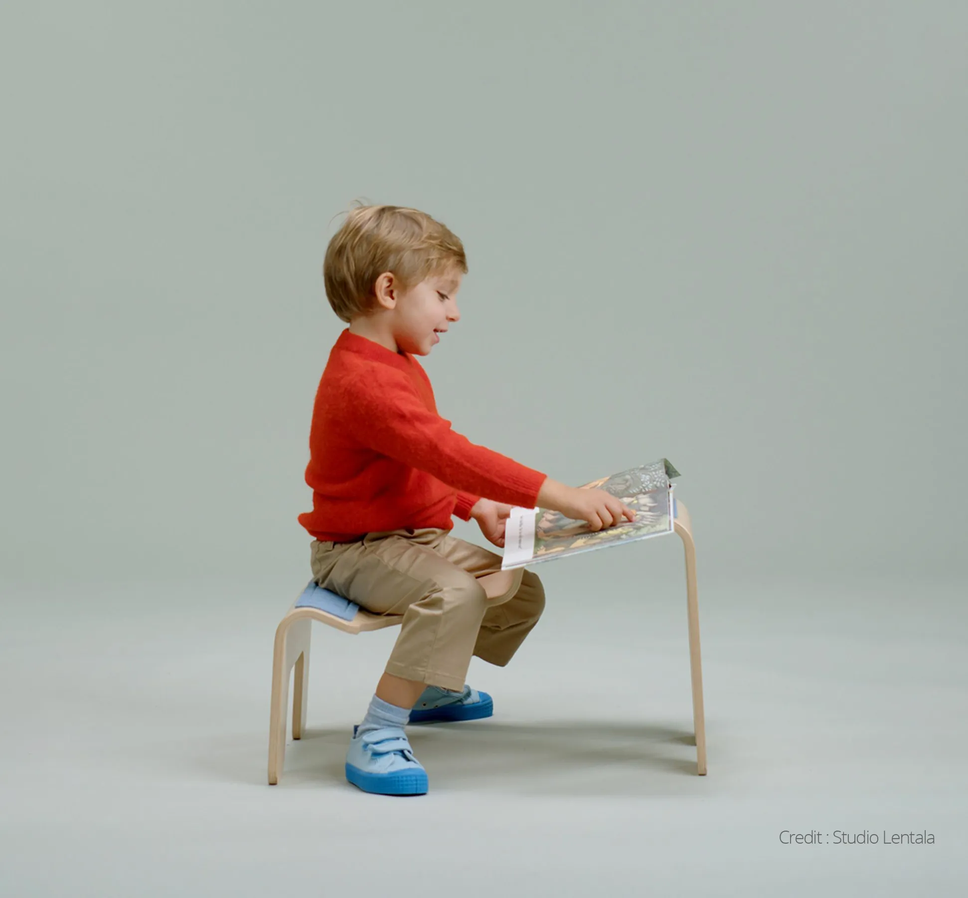 Child sitting on a stool in a red jumper