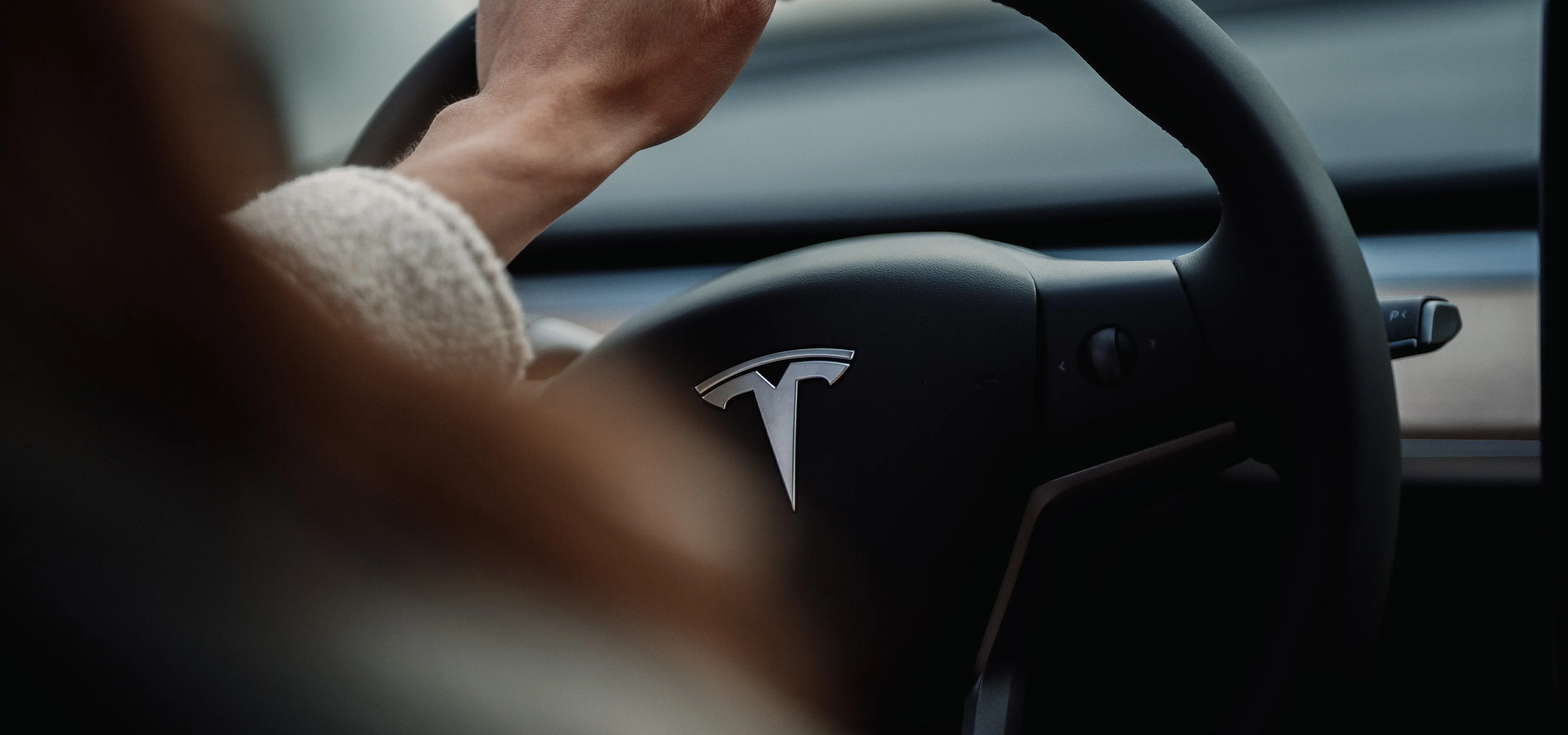 Hand on tesla steering wheel