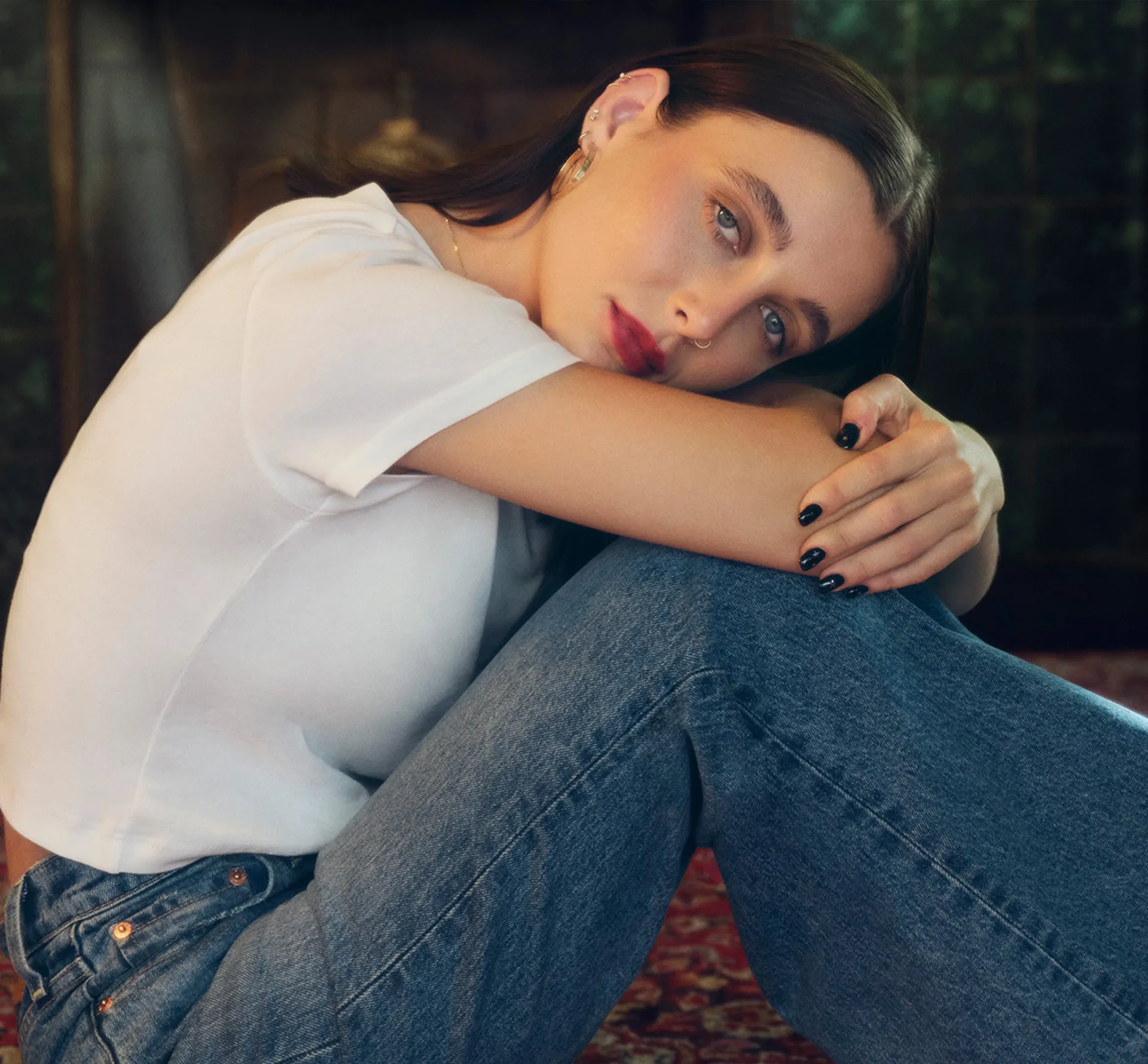 woman sitting in blue jeans and white T-shirt looking at camera