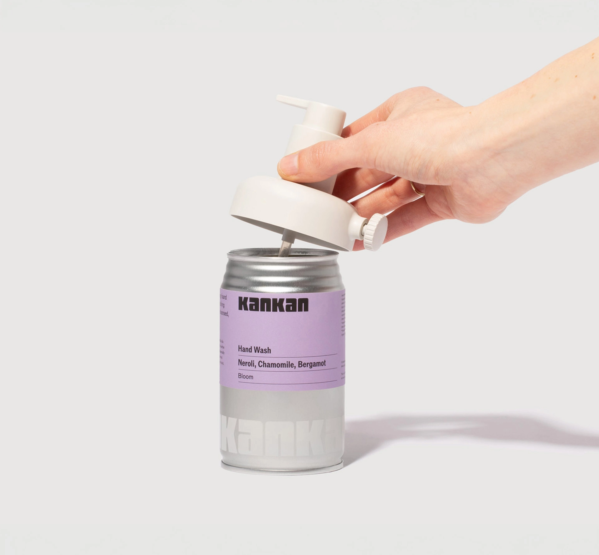 Body soap bottle from aluminium can with hand removing the dispenser