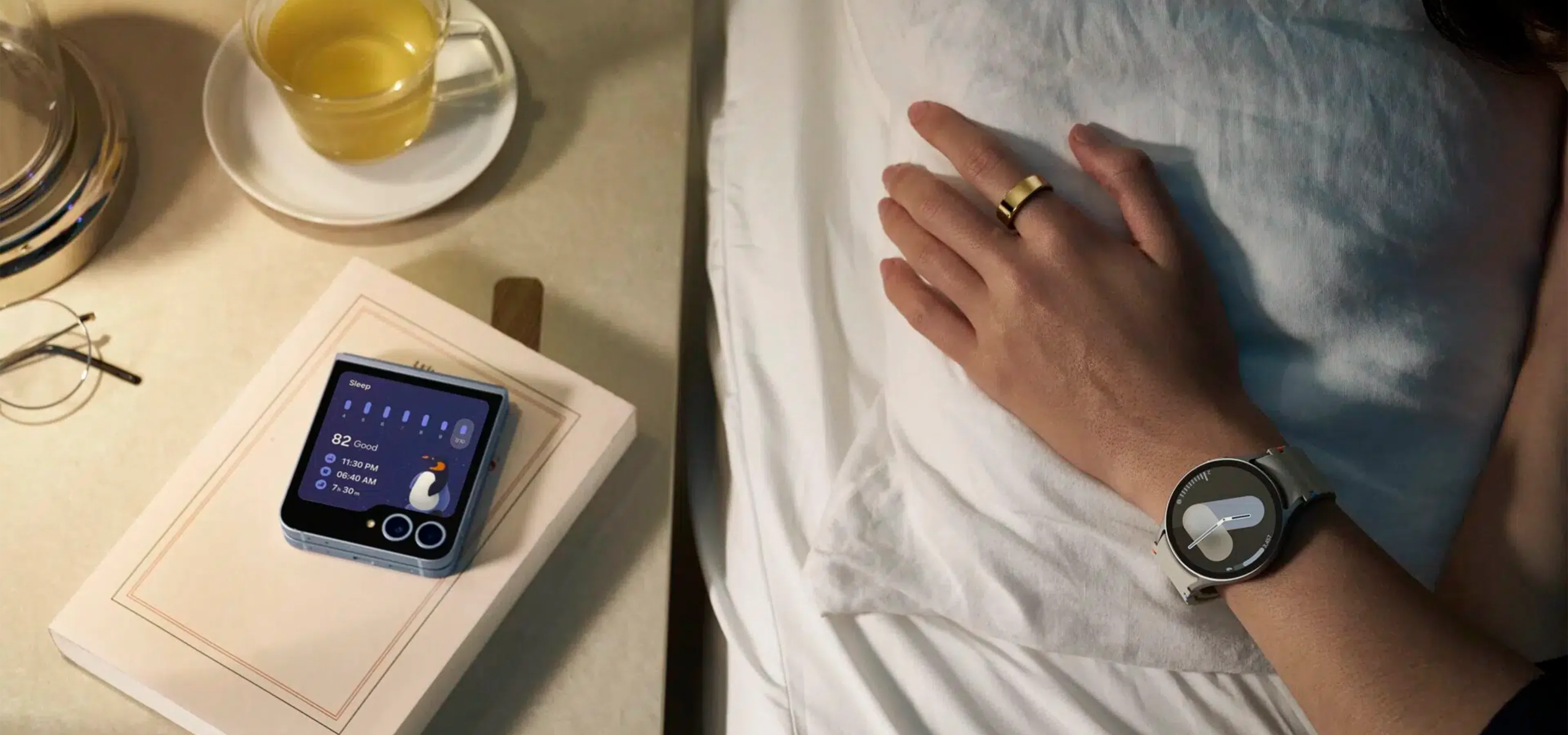 A detail shot of bedside table and an arm with Samsung watch and phone