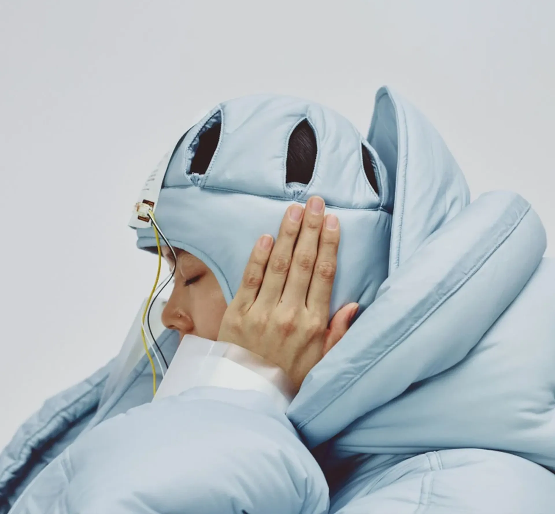 A person covering their ears in blue hat and jacket