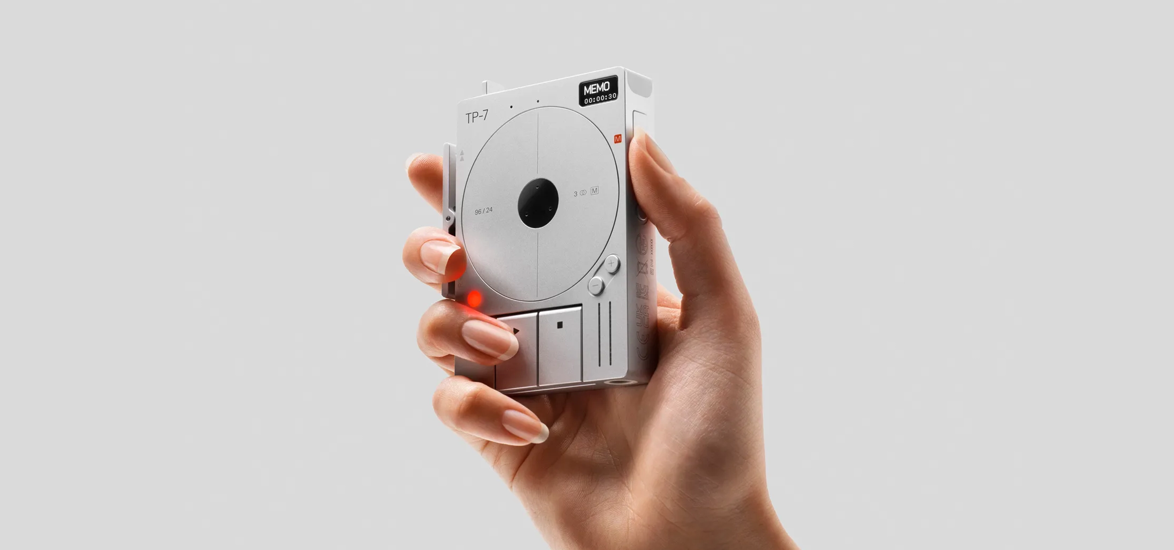 Hand holding a small silver recording device