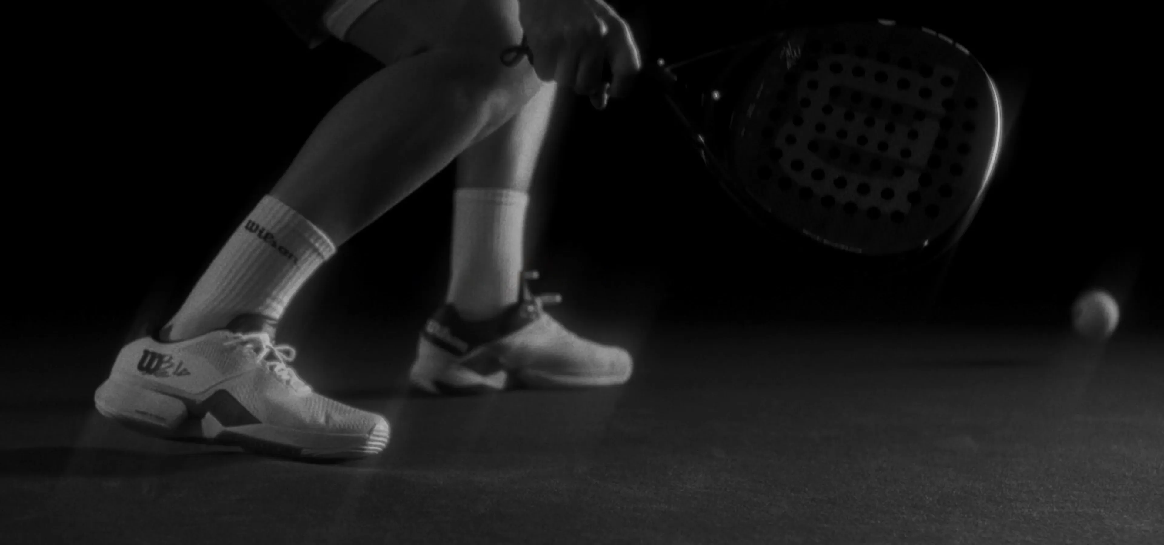 Black and white image of tennis player's feet and racquet