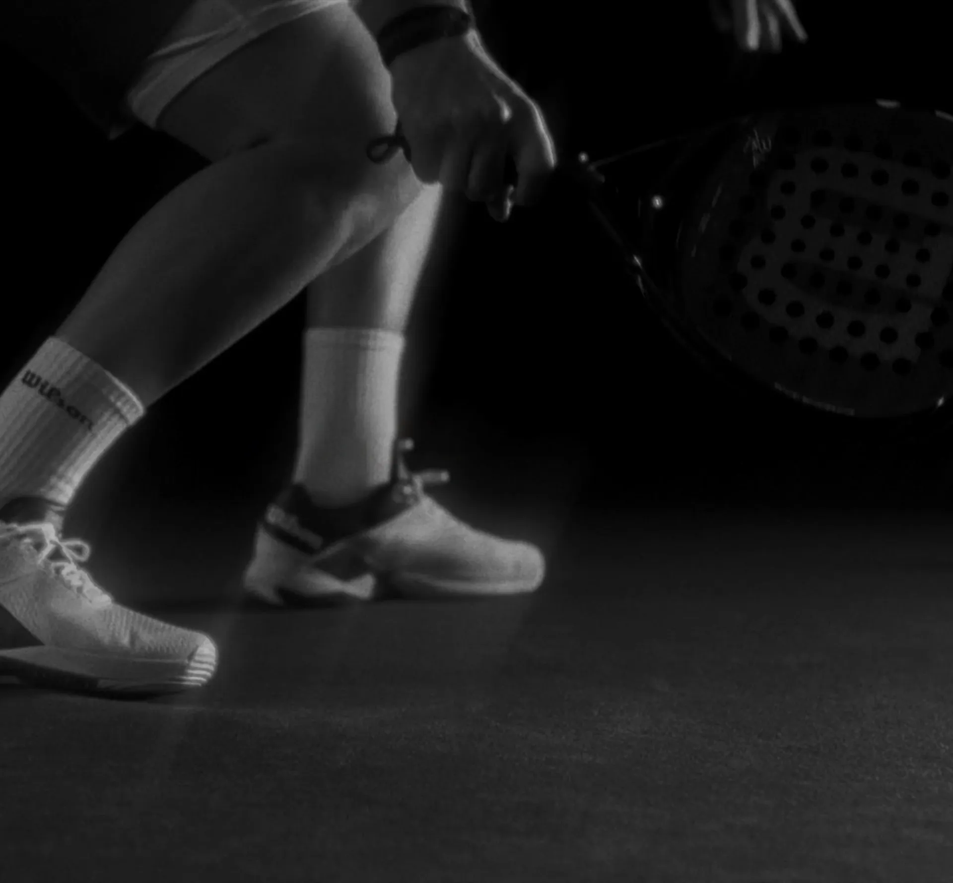 Black and white image of tennis player's feet and racquet