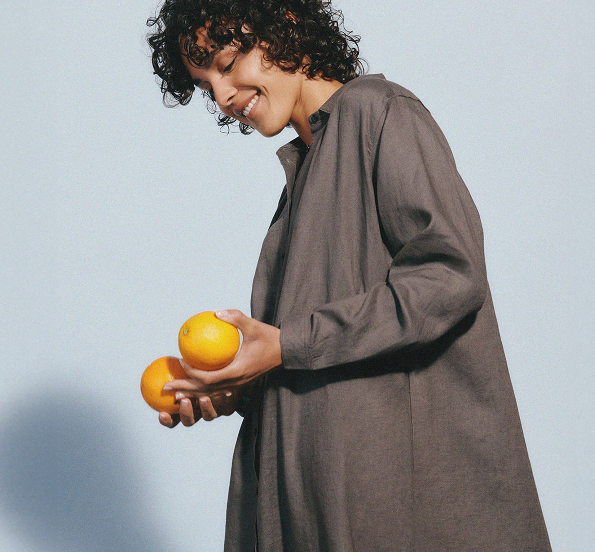 Woman in a long coat holding oranges