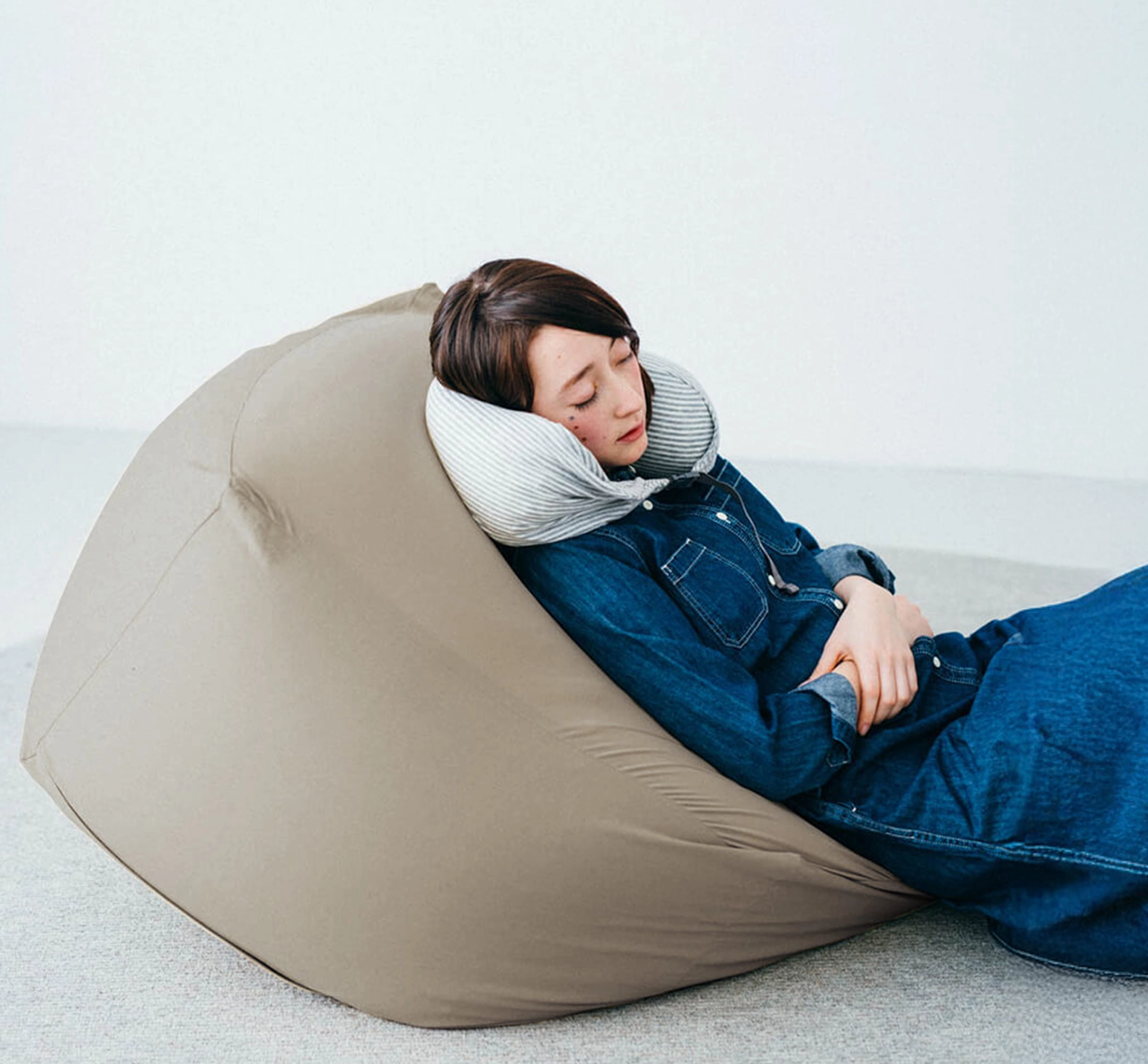 Woman dozing on a beanbag with a travel pillow
