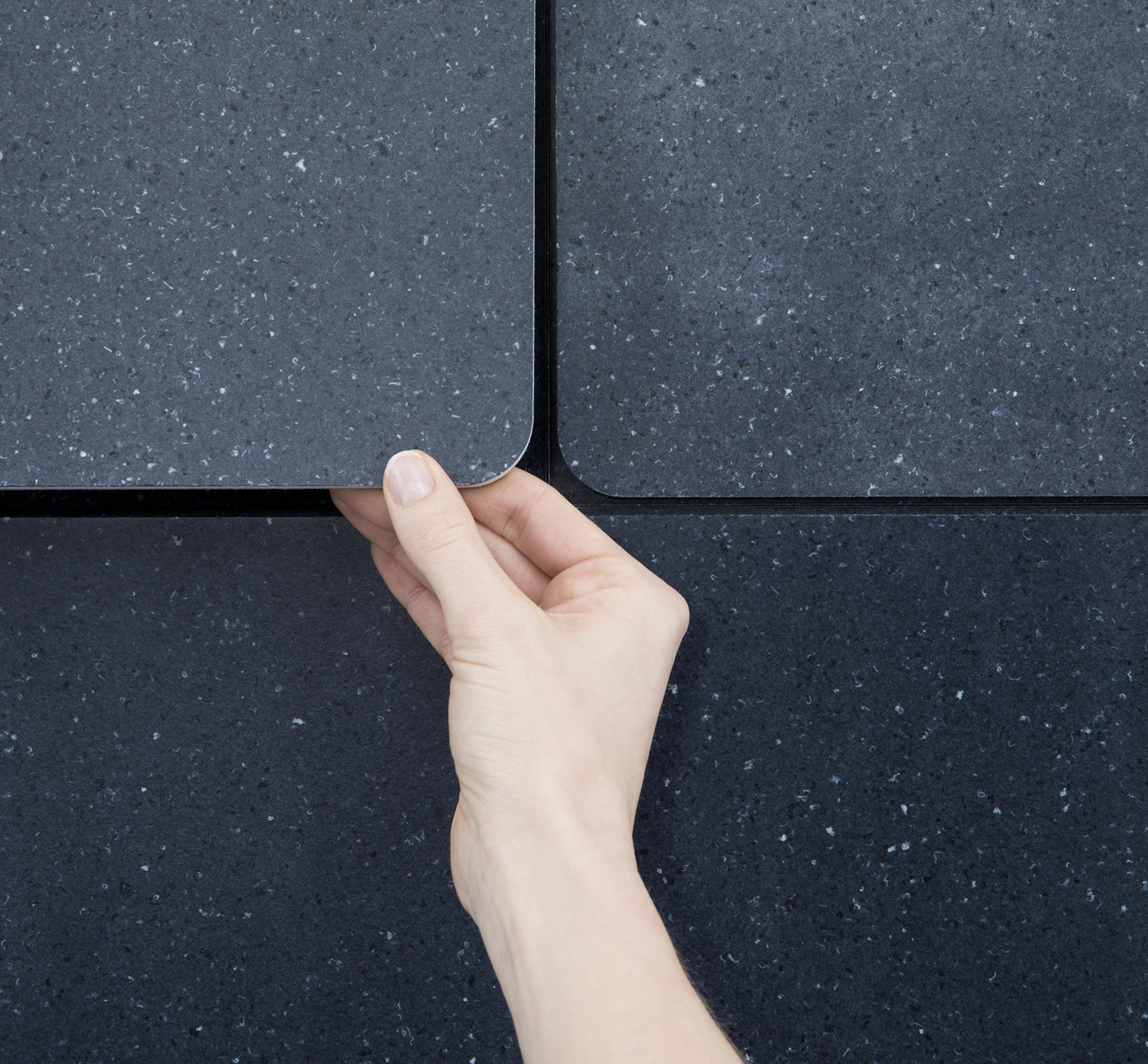 Hand holding a dark grey tile