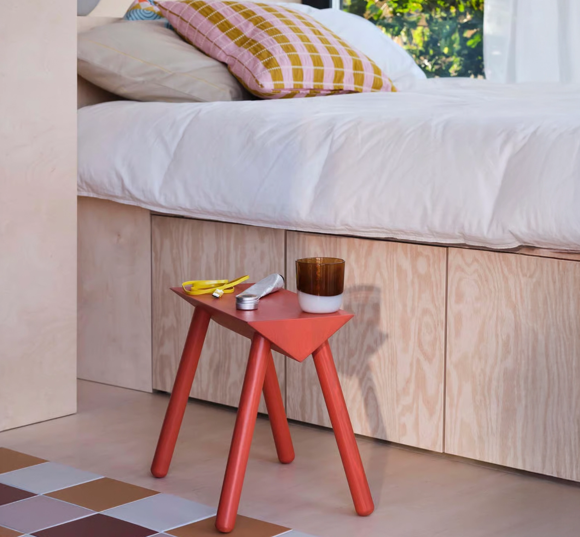 Small painted side table next to a bed